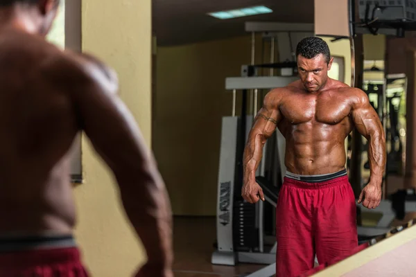 Shirtless bodybuilder posing at the mirror — Stock Photo, Image