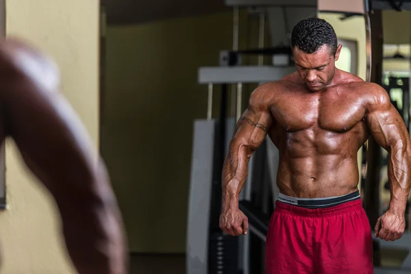 Shirtless bodybuilder posing at the mirror — Stock Photo, Image