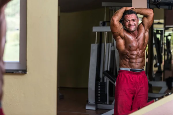 Bodybuilder showing abs at mirror — Stock Photo, Image