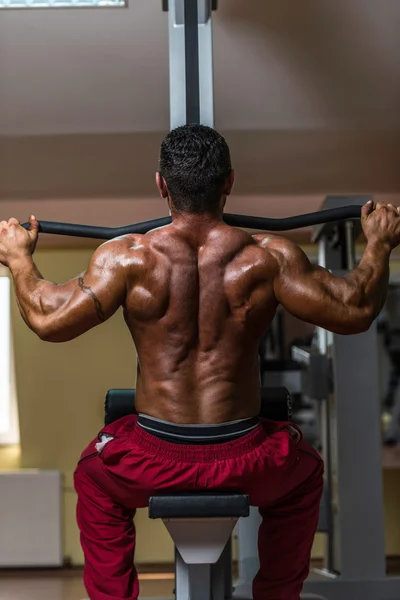 Fisicoculturista sin camisa haciendo ejercicio pesado para la espalda — Foto de Stock