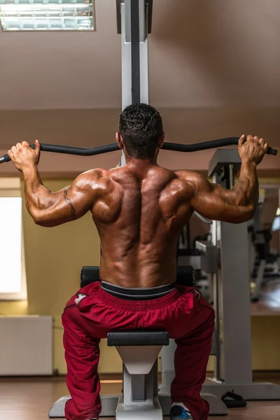 背部のための重い重量運動を行う上半身裸のボディービルダー — ストック写真