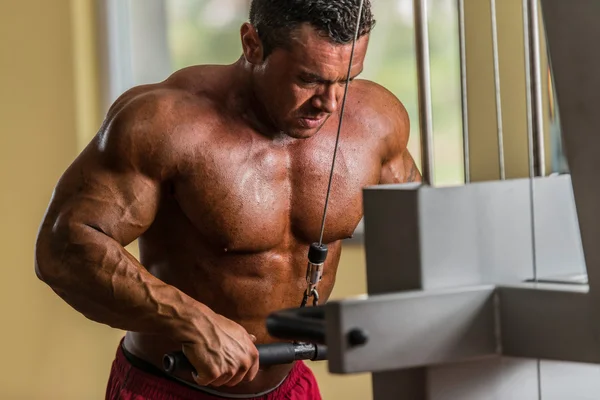 Bodybuilder doing heavy weight exercise for triceps with cable — Stock Photo, Image