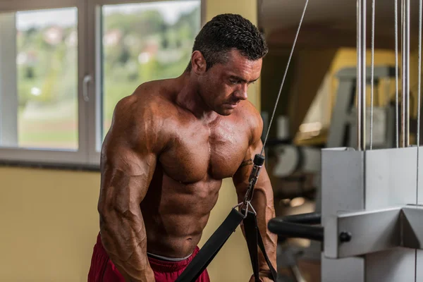 Bodybuilder doing heavy weight exercise for triceps with cable — Stock Photo, Image