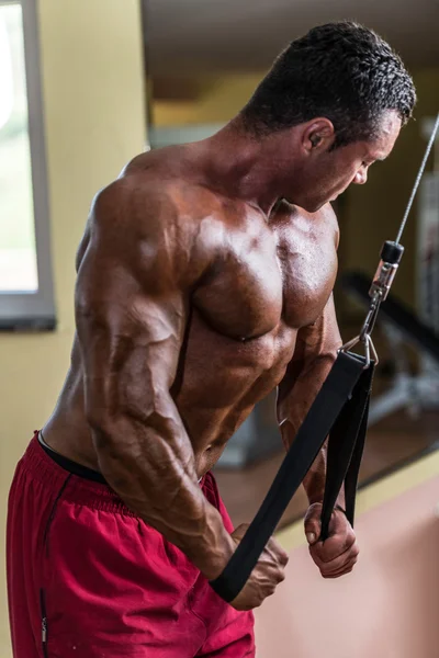 Bodybuilder doing heavy weight exercise for triceps with cable — Stock Photo, Image