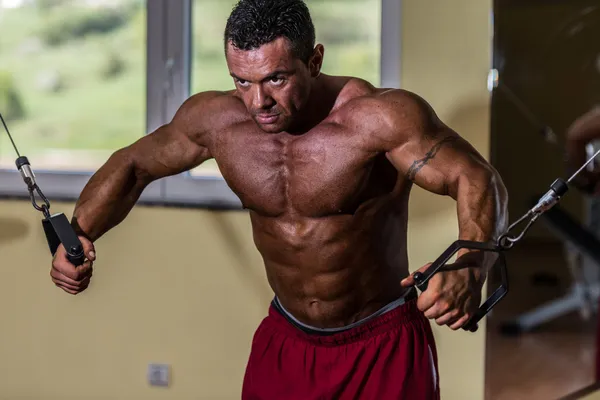 Shirtless body builder doing standing press white cable for chest — Stock Photo, Image