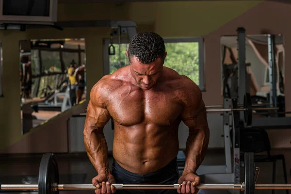 Bodybuilder doing heavy weight exercise for biceps with barbell — Stock Photo, Image