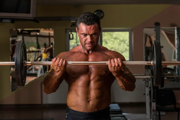 Bodybuilder doing heavy weight exercise for biceps with barbell — Stock Photo, Image