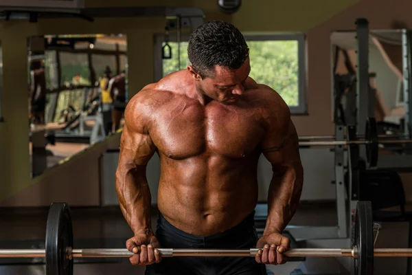 Bodybuilder doing heavy weight exercise for biceps with barbell — Stock Photo, Image