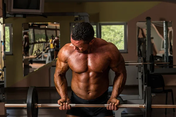 Kulturista dělat těžké váze cvičení pro biceps s činka — Stock fotografie