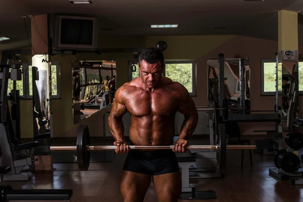 Bodybuilder doing heavy weight exercise for biceps with barbell — Stock Photo, Image