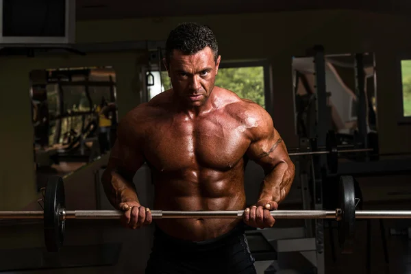 Bodybuilder doing heavy weight exercise for biceps with barbell — Stock Photo, Image