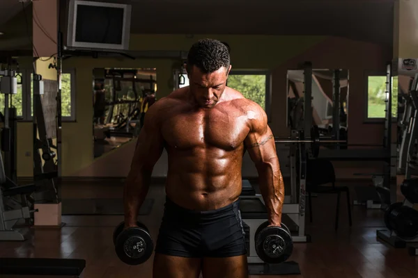 Body builder doing heavy weight exercise for biceps with dumbbell — Stock Photo, Image