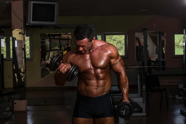 Body builder doing heavy weight exercise for biceps with dumbbell — Stock Photo, Image