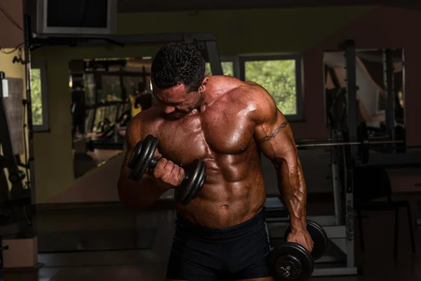 Body builder doing heavy weight exercise for biceps with dumbbell — Stock Photo, Image