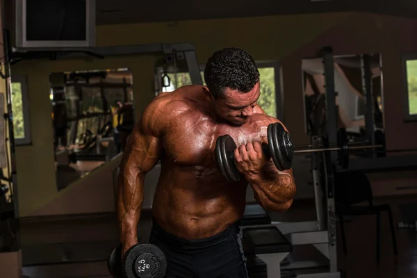 Body builder doing heavy weight exercise for biceps with dumbbell — Stock Photo, Image