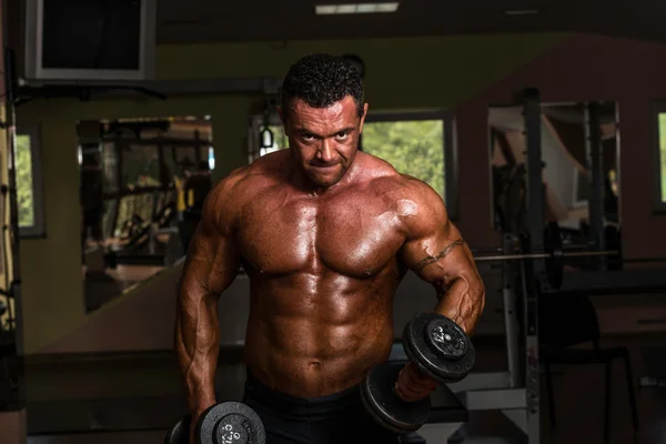 Budowniczy ciało robi ciężar ćwiczeń na biceps z hantle — Zdjęcie stockowe
