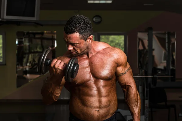 Body builder doing heavy weight exercise for biceps with dumbbell — Stock Photo, Image