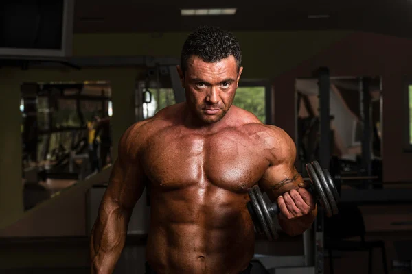 Body builder doing heavy weight exercise for biceps with dumbbell — Stock Photo, Image