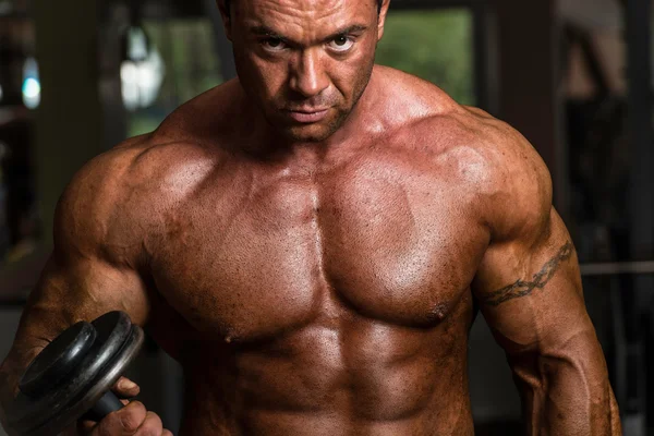 Shirtless body builder posing with dumbbell at the bench — Stock Photo, Image