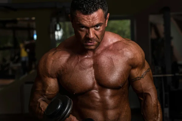 Shirtless body builder posing with dumbbell at the bench — Stock Photo, Image