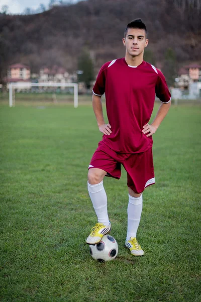 Jeune footballeur avec ballon sur le terrain en robe rouge — Photo