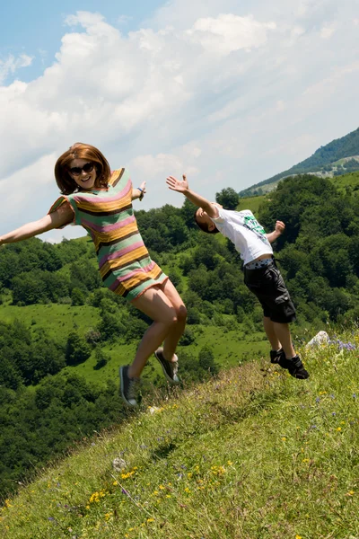 Mother and son jumping in meadow — Stock Photo, Image