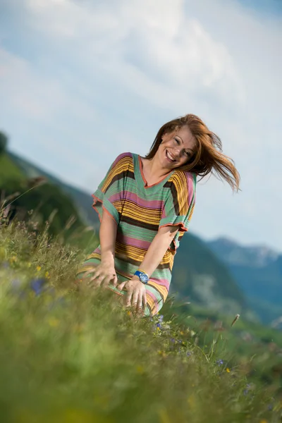 Mooie vrouw in jurk zittend op het gras — Stockfoto