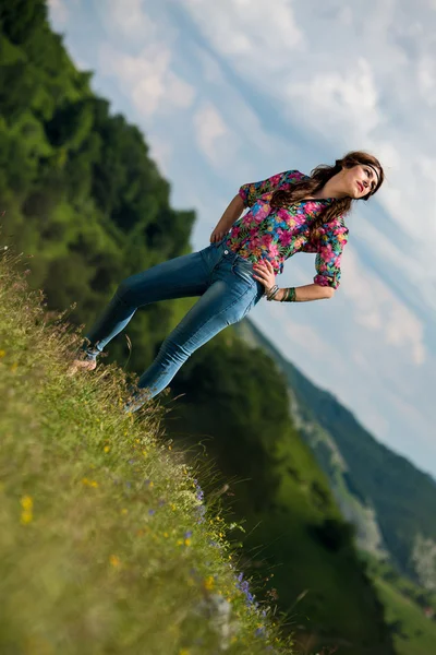 Beautiful woman in jeans standing on the grass — Stock Photo, Image