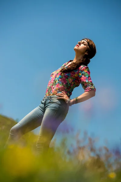 Vacker kvinna i jeans står på gräset — Stockfoto