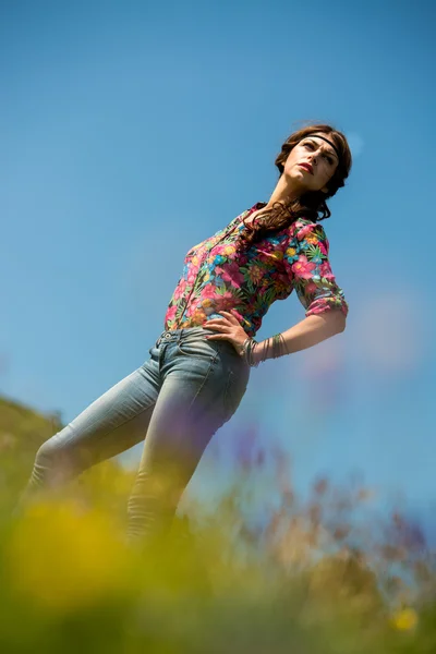 Hermosa mujer en jeans de pie sobre la hierba —  Fotos de Stock