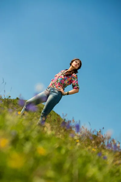 Vacker kvinna i jeans står på gräset — Stockfoto