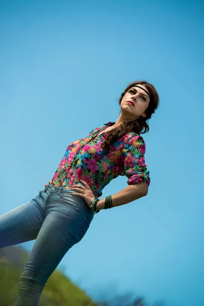 Beautiful woman in jeans standing on the grass — Stock Photo, Image