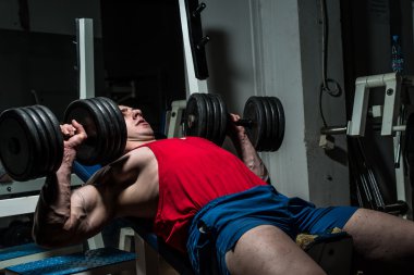 Genç vücut geliştirici göğüs için göğüs presi yapıyor.