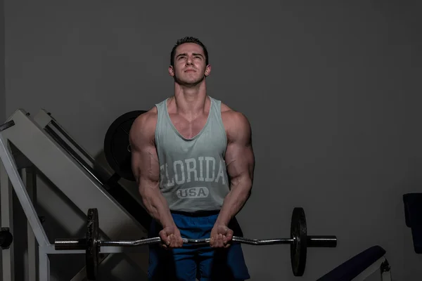 Young bodybuilder doing heavy weight exercise for biceps with ba — Stock Photo, Image