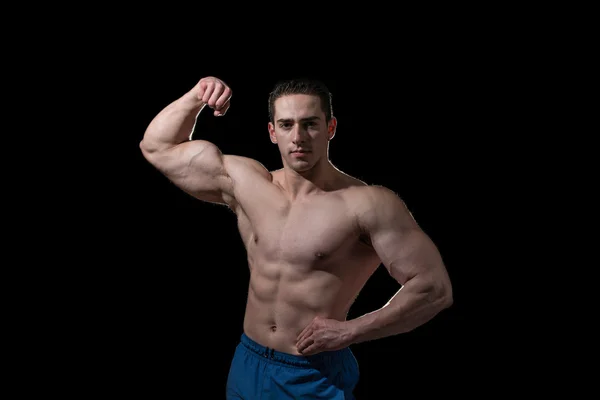 Kulturysta, pokazano jego biceps na czarnym tle — Zdjęcie stockowe