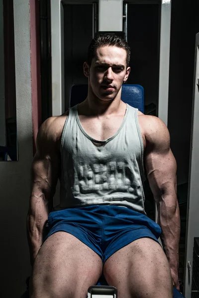 Bodybuilder doing heavy weight exercise for legs on machine leg extensions — Stock Photo, Image