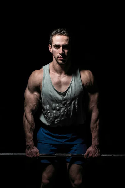 Young bodybuilder posing on black background — Stock Photo, Image