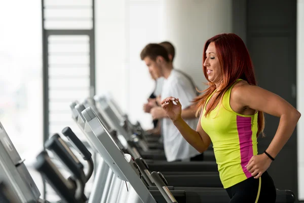 Mujer joven corriendo en cintas de correr — Foto de Stock