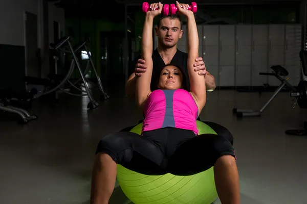 Mulher se exercitando no ginásio com personal trainer — Fotografia de Stock