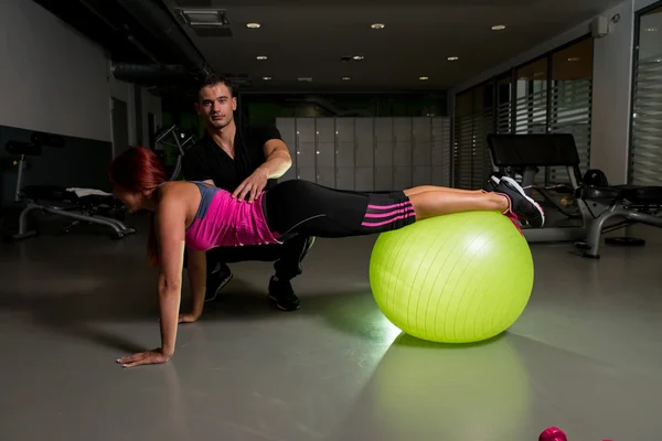 Jovem mulher e personal trainer no ginásio — Fotografia de Stock