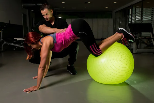 Vrouw trainen in de fitnessruimte met personal trainer — Stockfoto