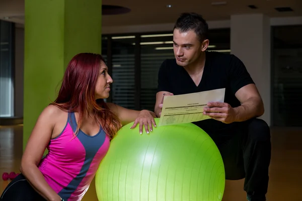 Donna adulta con personal trainer in palestra — Foto Stock