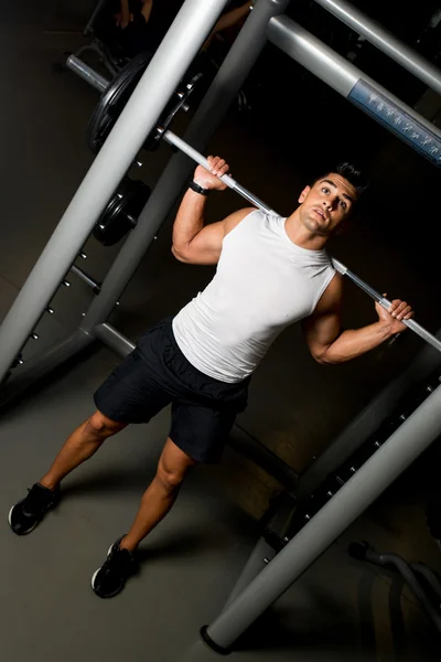 Giovane uomo in bianco T-shirt facendo bilanciere squat — Foto Stock