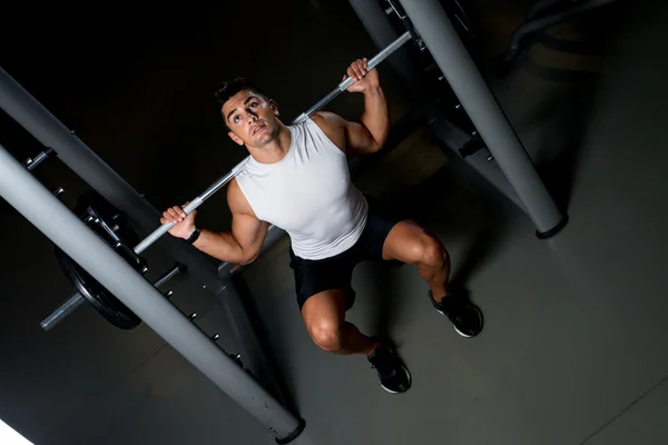 Giovane uomo che esercita con squat bilanciere — Foto Stock