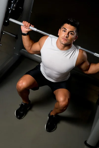 Ung man i vit t-shirt gör barbell knäböj — Stockfoto