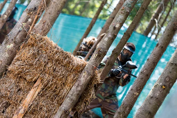 Paintballspieler verstecken sich hinter Baum — Stockfoto