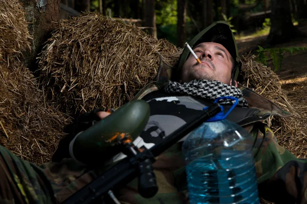 Пейнтболист отдыхает и курит сигару — стоковое фото