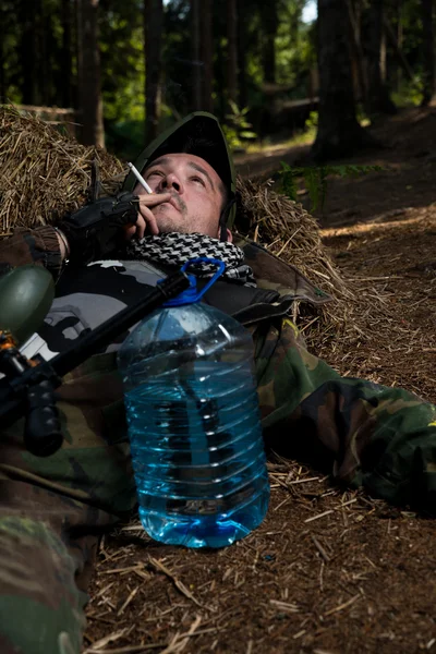 Paintball player resting and smoking a cigar — Stock Photo, Image