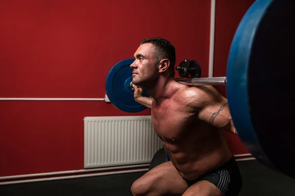 Bodybuilder doing squats with barbells — Stock Photo, Image