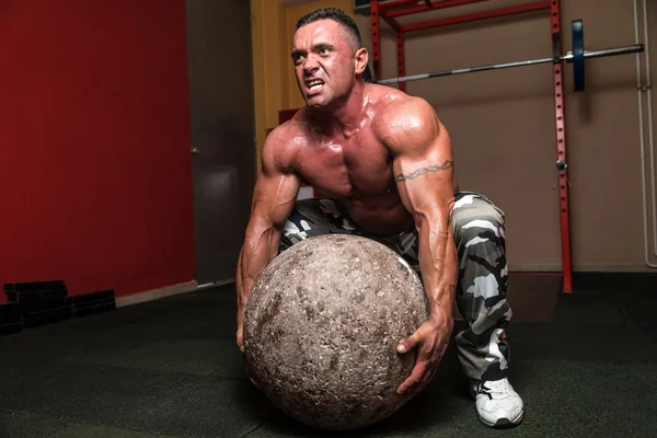 Bodybuilder versucht, einen Stein aufzuheben — Stockfoto